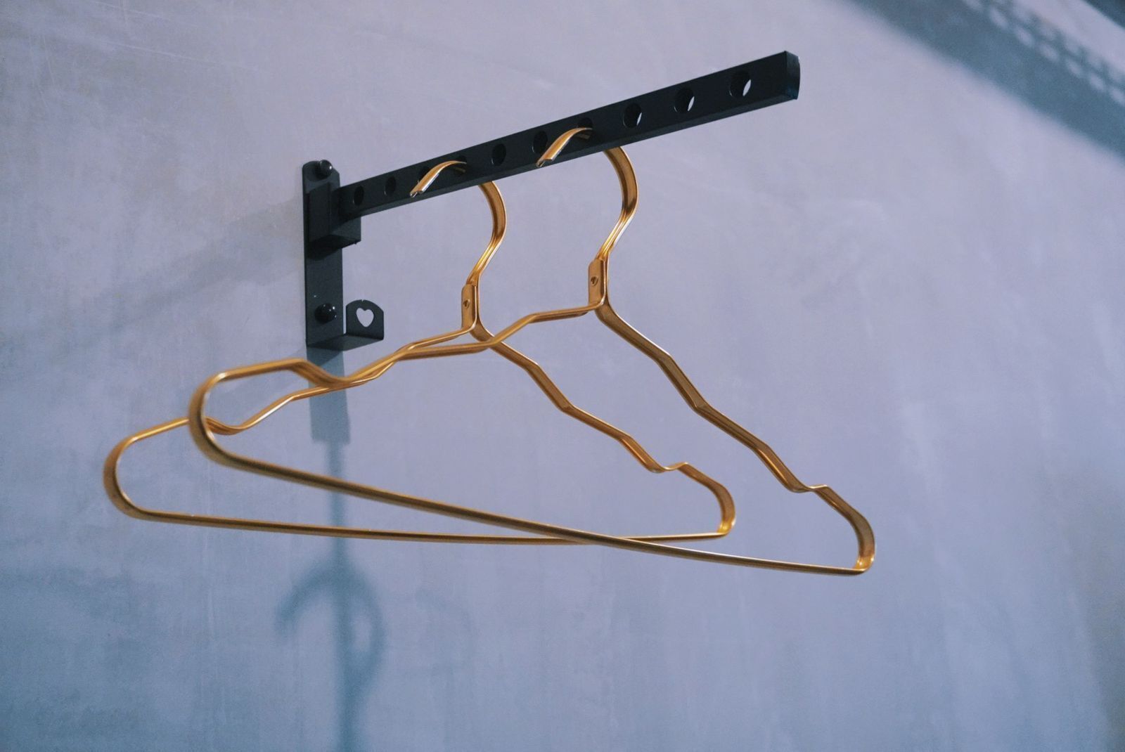 A hanger with a black metal stand and a gold-colored wire hanger.