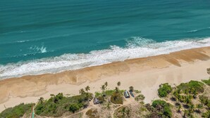 Une plage avec une eau d’un bleu limpide, un rivage sablonneux et quelques palmiers.