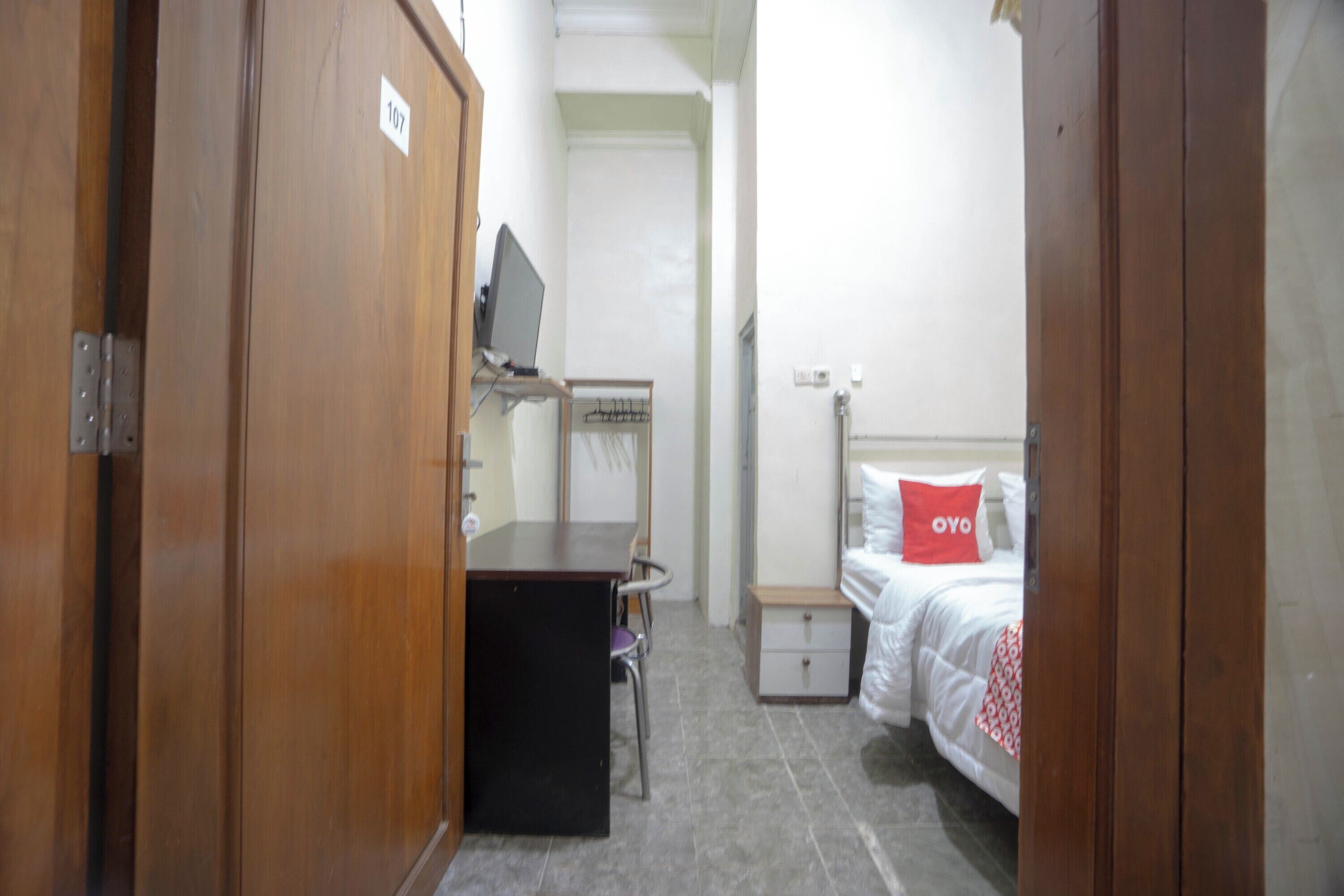 A small, neatly arranged bedroom with a bed, a desk, and a chair.
