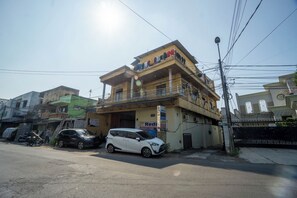 A multi-story building with balconies, a sign for a business, and parked cars. - OYO 93987 Suropati 2 Guest House (Malang)