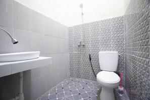 A bathroom with a white sink, toilet, and shower. The floor has a geometric tile pattern. - OYO 93987 Suropati 2 Guest House (Malang)