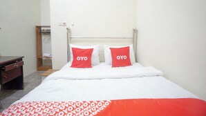 Una habitación de hotel con una cama, una mesita de noche de madera y un armario.
