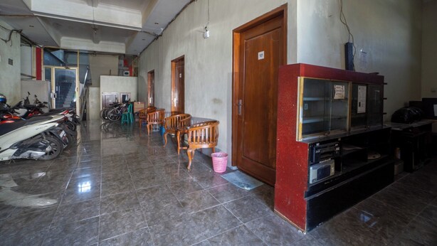 A hallway with tiled flooring, wooden doors, a staircase, and a seating area with chairs and a table. - OYO 93987 Suropati 2 Guest House (Malang)