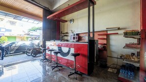 Un restaurante con mostrador rojo, taburetes, un reloj y un refrigerador.