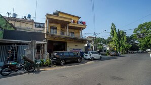 Vista de la calle con un edificio de dos plantas, una motocicleta estacionada y varios automóviles.