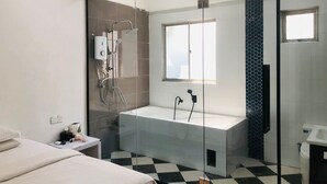 A modern bathroom with a glass shower enclosure, a freestanding bathtub, and a window providing natural light. - The Ardens Hotel - Sentosa - Johor Bahru (Johor Bahru)