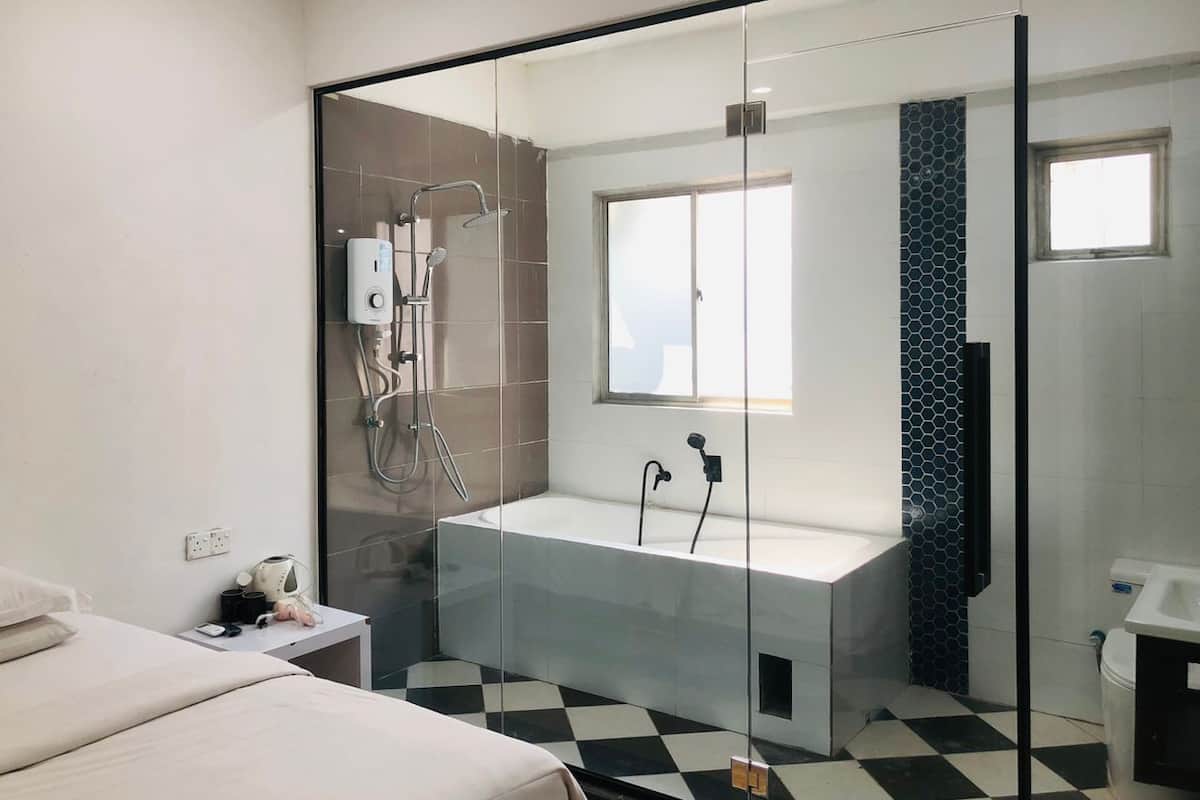 Une salle de bain moderne dotée d’une douche à parois de verre, d’une baignoire sur pieds et d’une fenêtre laissant entrer la lumière naturelle.
