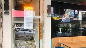 A hotel entrance with a neon 'OPEN' sign, a 'WELCOME' sign, and a 'PAPPA' sign with a cartoon character. - The Ardens Hotel - Sentosa - Johor Bahru (Johor Bahru)