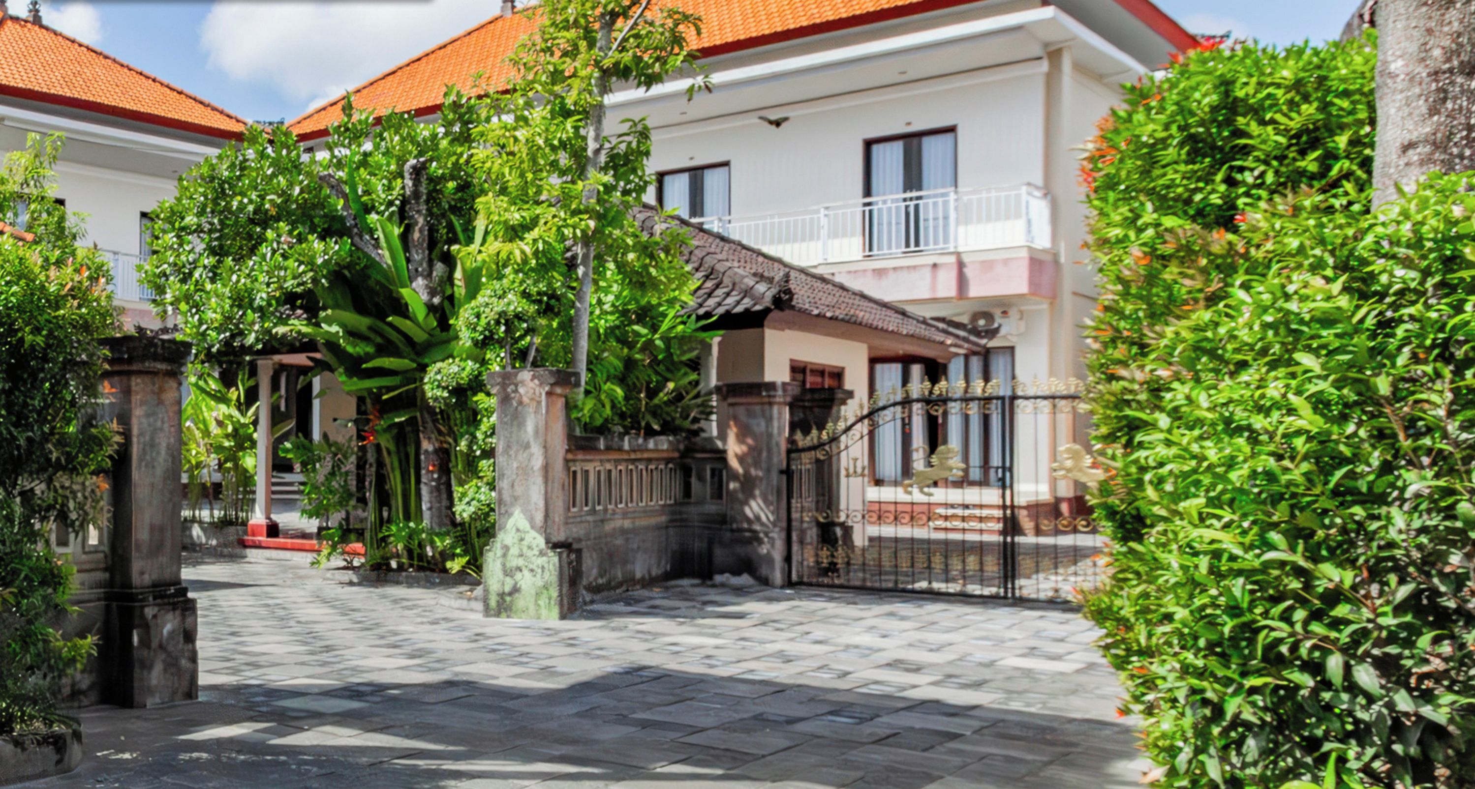 A two-story house with a tiled roof, a gated entrance, and a well-maintained garden.