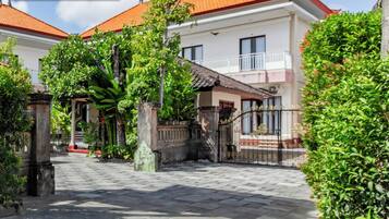 A two-story house with a tiled roof, a gated entrance, and a well-maintained garden.