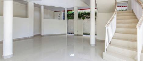 A spacious, modern interior with a central open area, a staircase, and a columned corridor.