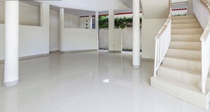 A spacious, modern interior with a central open area, a staircase, and a columned corridor. - Collection O Near Seminyak Beach Formerly The Kumpi Hotel (Seminyak)