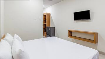 A bedroom with a bed, a television mounted on the wall, and a small wooden shelf.