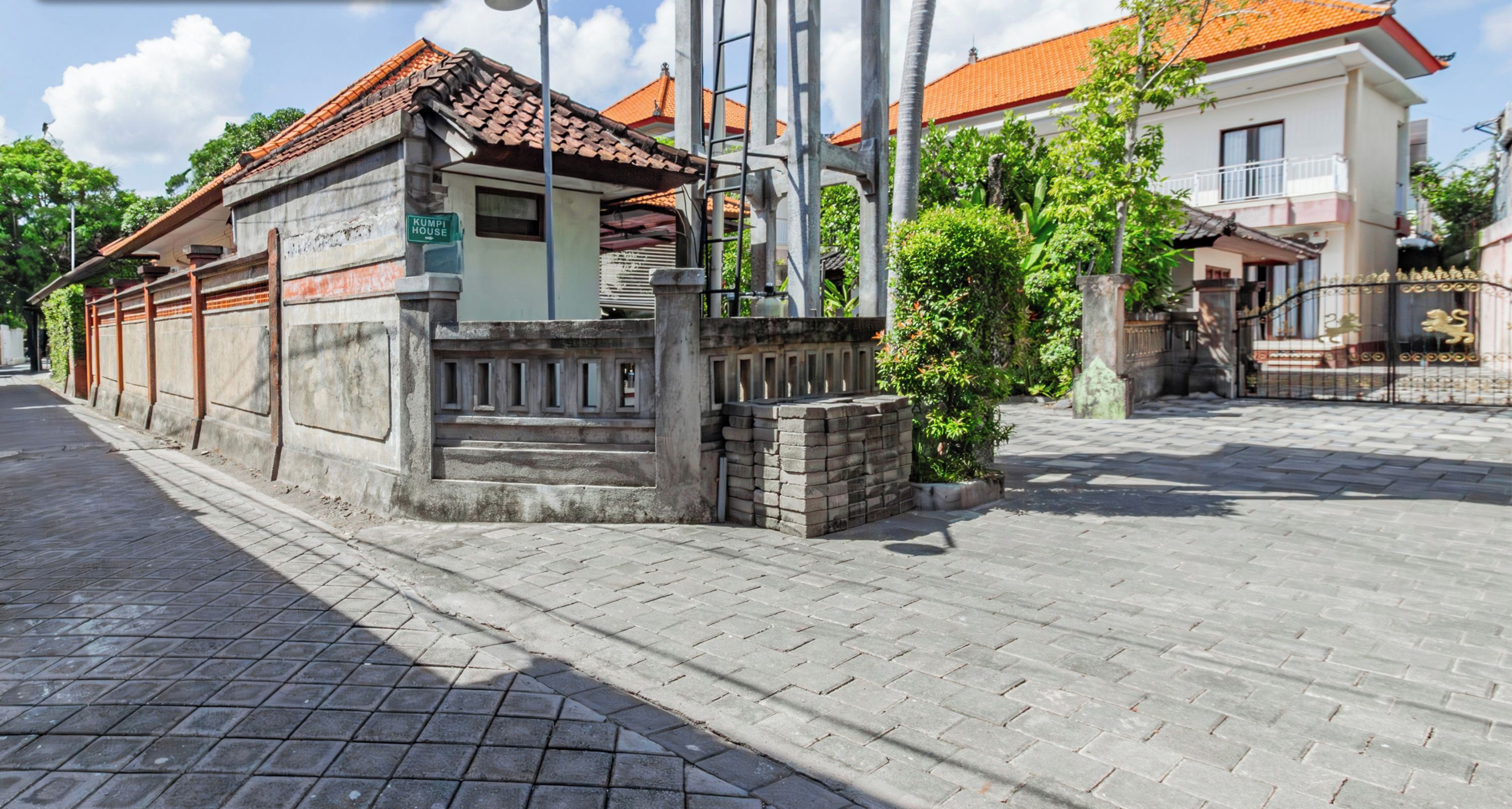 A traditional building with a tiled roof, a stone wall, and a sign that reads "Rumah House".