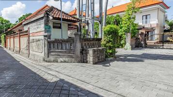 A traditional building with a tiled roof, a stone wall, and a sign that reads "Rumah House".