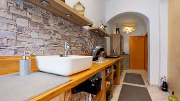A modern bathroom with a stone wall, wooden vanity, and a large sink.