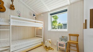 Habitación con literas, una ventana, una mesita pequeña y un caballo balancín.