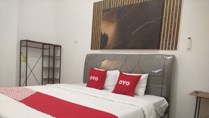 Ein ordentlich bezogenes Bett mit einer roten und weißen Bettdecke und zwei Kissen mit dem Schriftzug "OYO".