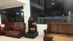 Ein Wohnbereich mit zwei Holzsofas, einem kleinen Tisch und einem dekorativen Stapel Keramikgefäßen.
