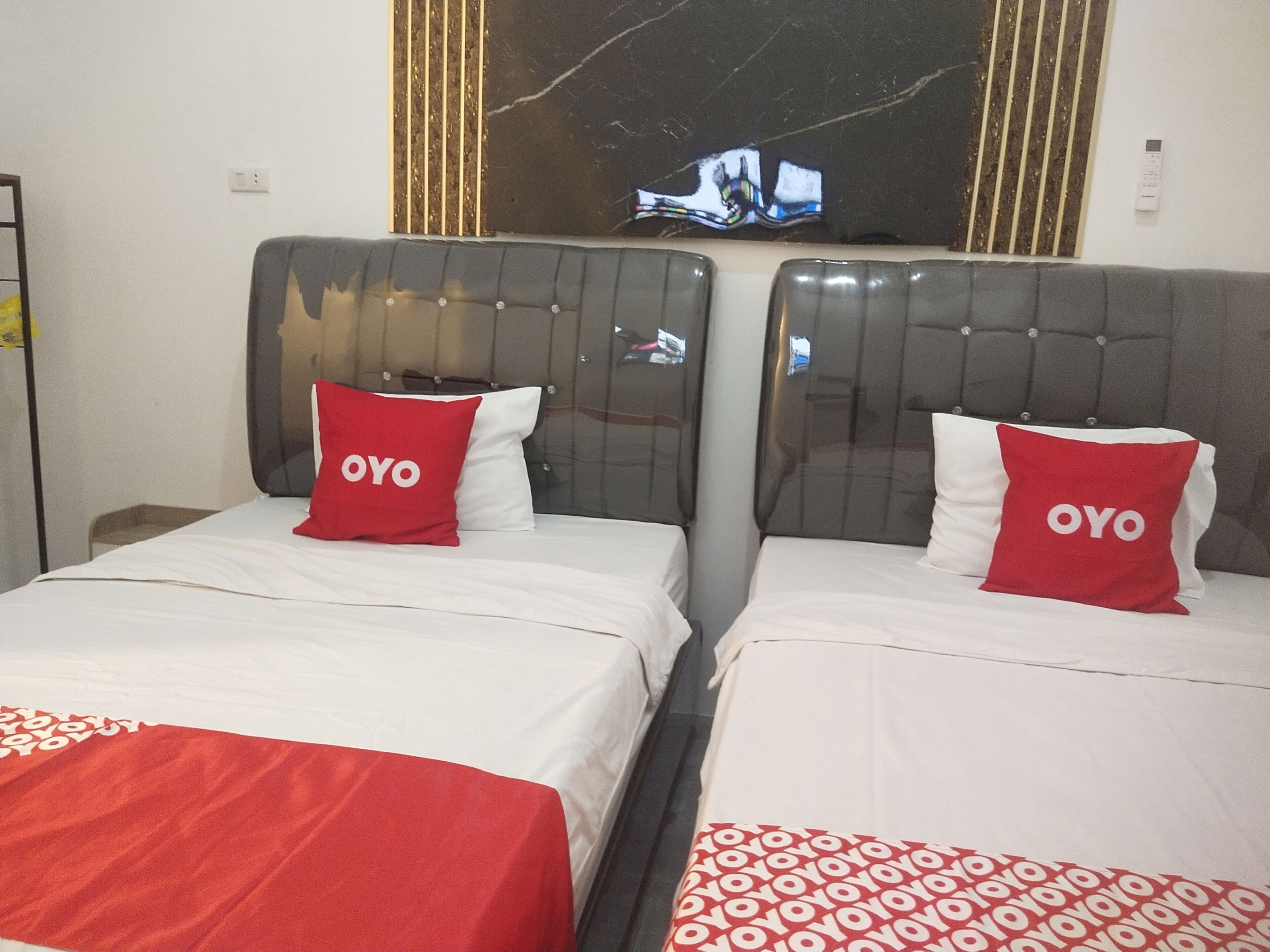 A hotel room with two beds, each with a headboard and a pillow with the word "OYO".