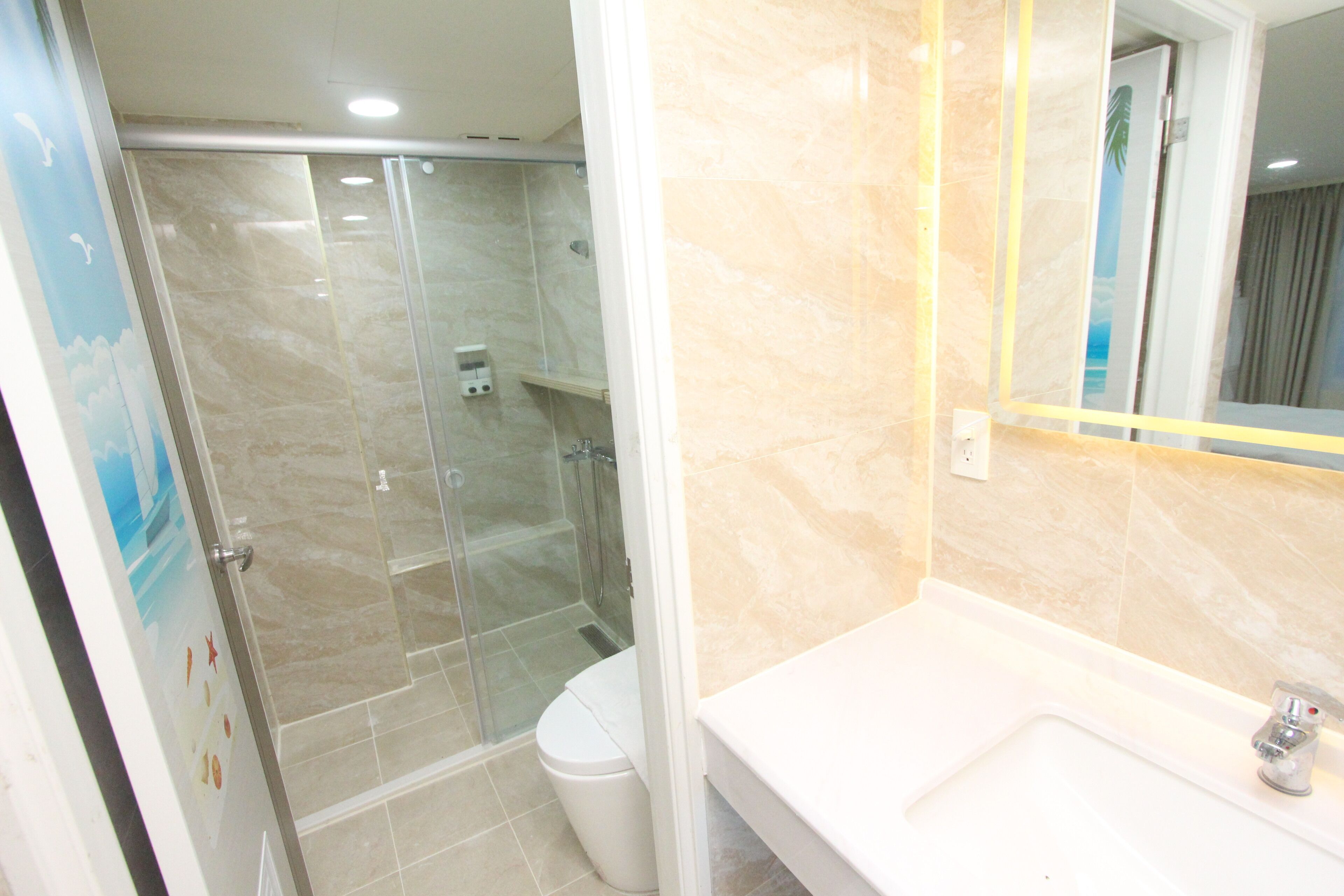 A bathroom with a glass-enclosed shower, a white sink, and a mirror with a yellow frame.