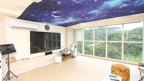 Una habitación con techo estrellado, ventanas amplias, un piano y un televisor.