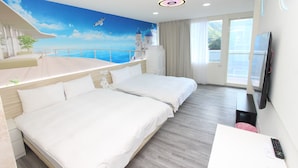 Habitación de hotel con dos camas, televisión, escritorio y balcón con vista al mar.