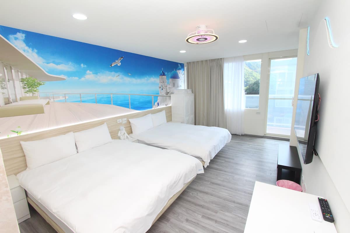 Une chambre d’hôtel avec deux lits, une télévision, un bureau et un balcon donnant sur la mer.