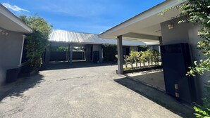 A covered parking area with a gravel surface, a metal roof, and a clear sky. - Phatra Resort (Saraburi)