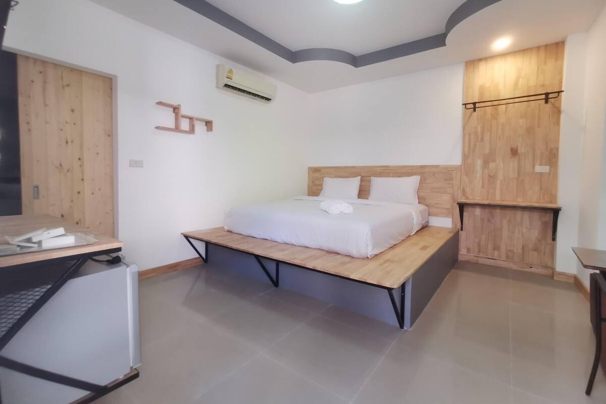A bedroom with a bed, a desk, and a wardrobe.