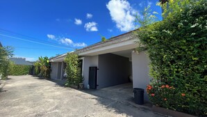 A residential building with a covered driveway, a black door, and a trash bin. - Phatra Resort (Saraburi)