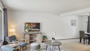 A modern living room with a flat-screen TV, comfortable seating, a dining area, and a cozy fireplace. - Entire home in Port Orchard, Washington with Game Room, Fire Pit and RV Parking (Port Orchard)