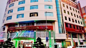 Un hotel de varios pisos con fachada curva, múltiples balcones y diversa señalización que indica diferentes servicios e instalaciones.