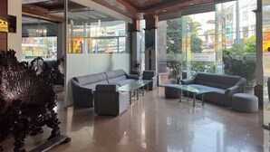 Un vestíbulo moderno con techo de madera, paredes de vidrio y una zona de estar con sofás y una mesa de centro.
