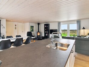 Une cuisine moderne dotée d'un îlot central, d'un coin repas avec des chaises, d'un canapé et d'une vue sur l'extérieur.