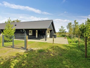 Un bâtiment moderne doté d’un toit en métal et d’une zone délimitée par une clôture.