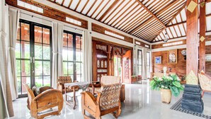 Una habitación amplia con techo alto, muebles de madera y ventanas grandes.