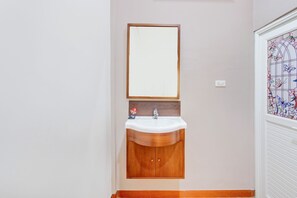 A bathroom with a wooden vanity, a white sink, and a mirror above it. - Capital O 93994 Dalem Kamulyan Syariah Guest House (Pakem)