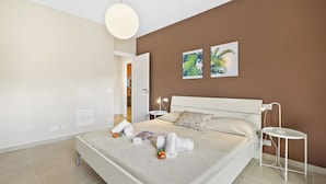 A modern bedroom with a bed, bedside tables, a nightstand, a hanging light, and two wall art pieces. - The Golden View: 2-bed Apartment w/ AC (Belgirate)