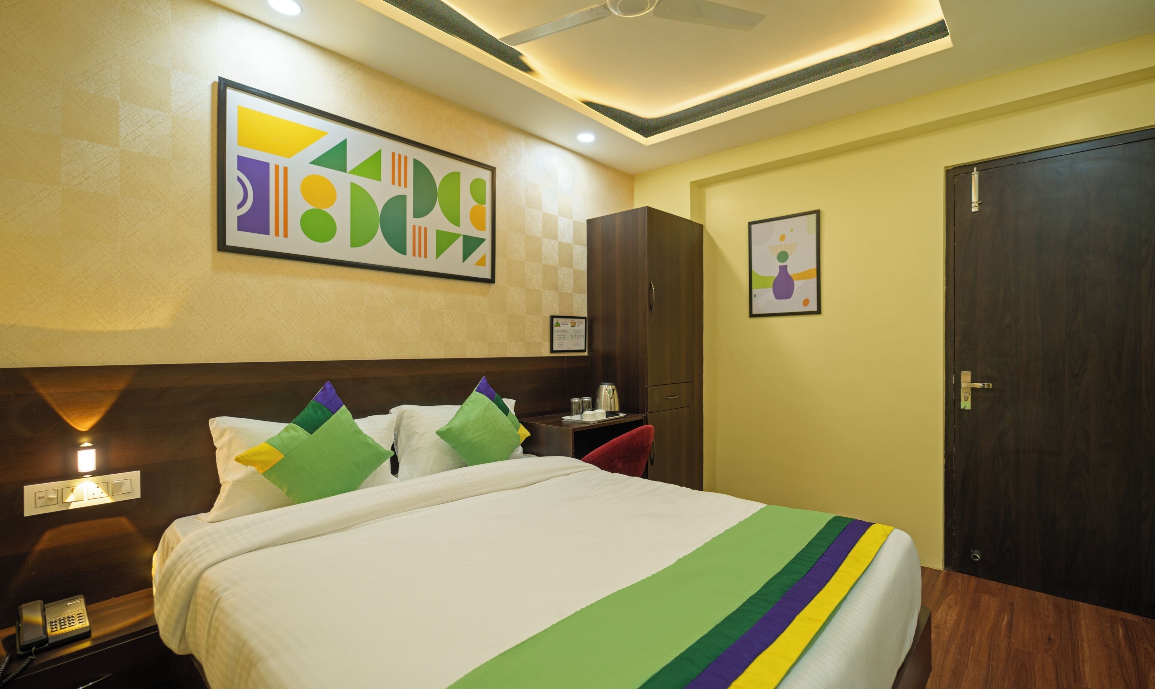 Una habitación de hotel con cama, mesita de noche, teléfono, armario y puerta.