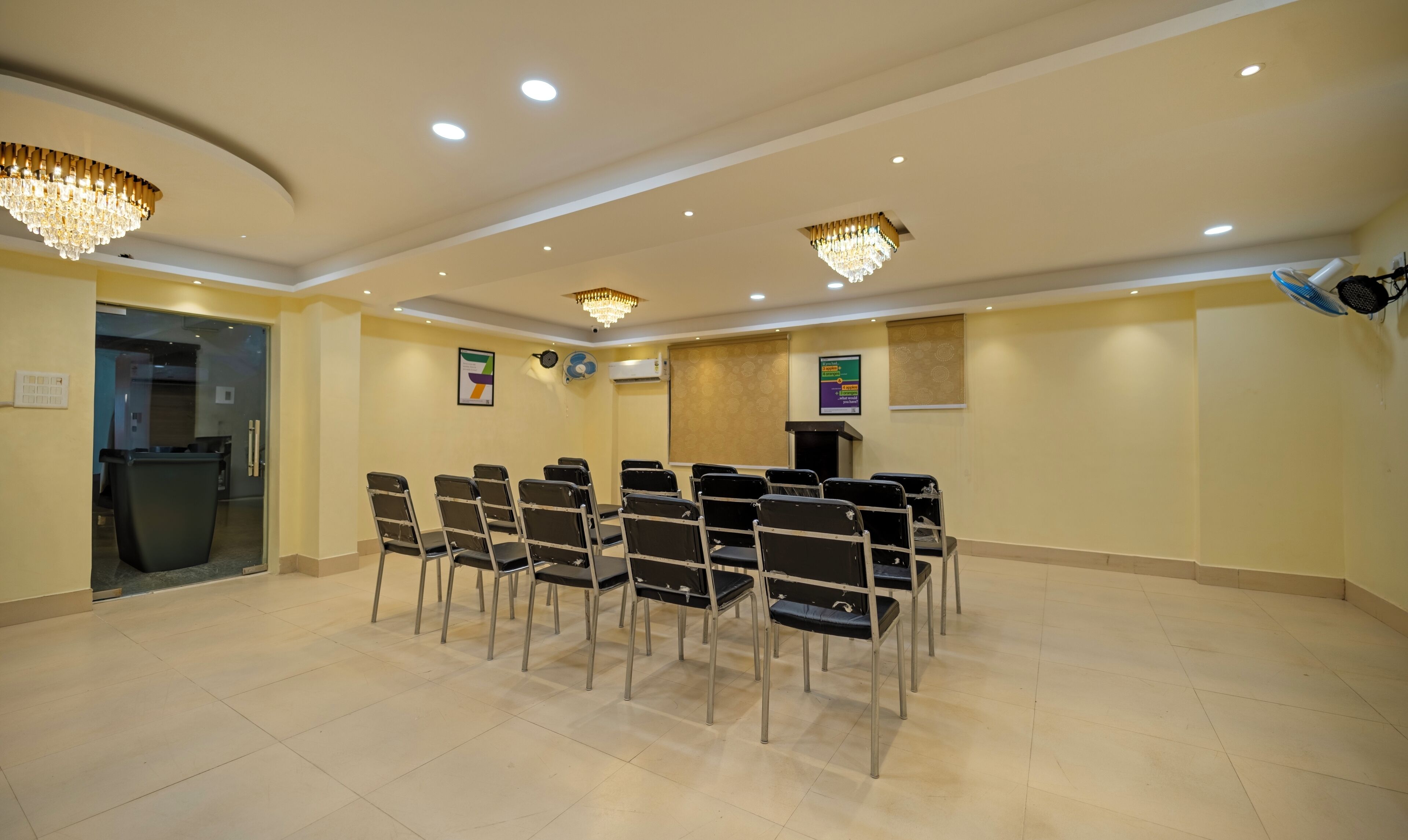 A conference room with rows of chairs, a podium, and chandeliers.