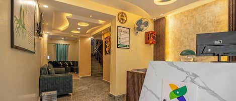 A reception area with a marble counter, a logo, and a staircase leading to another floor.