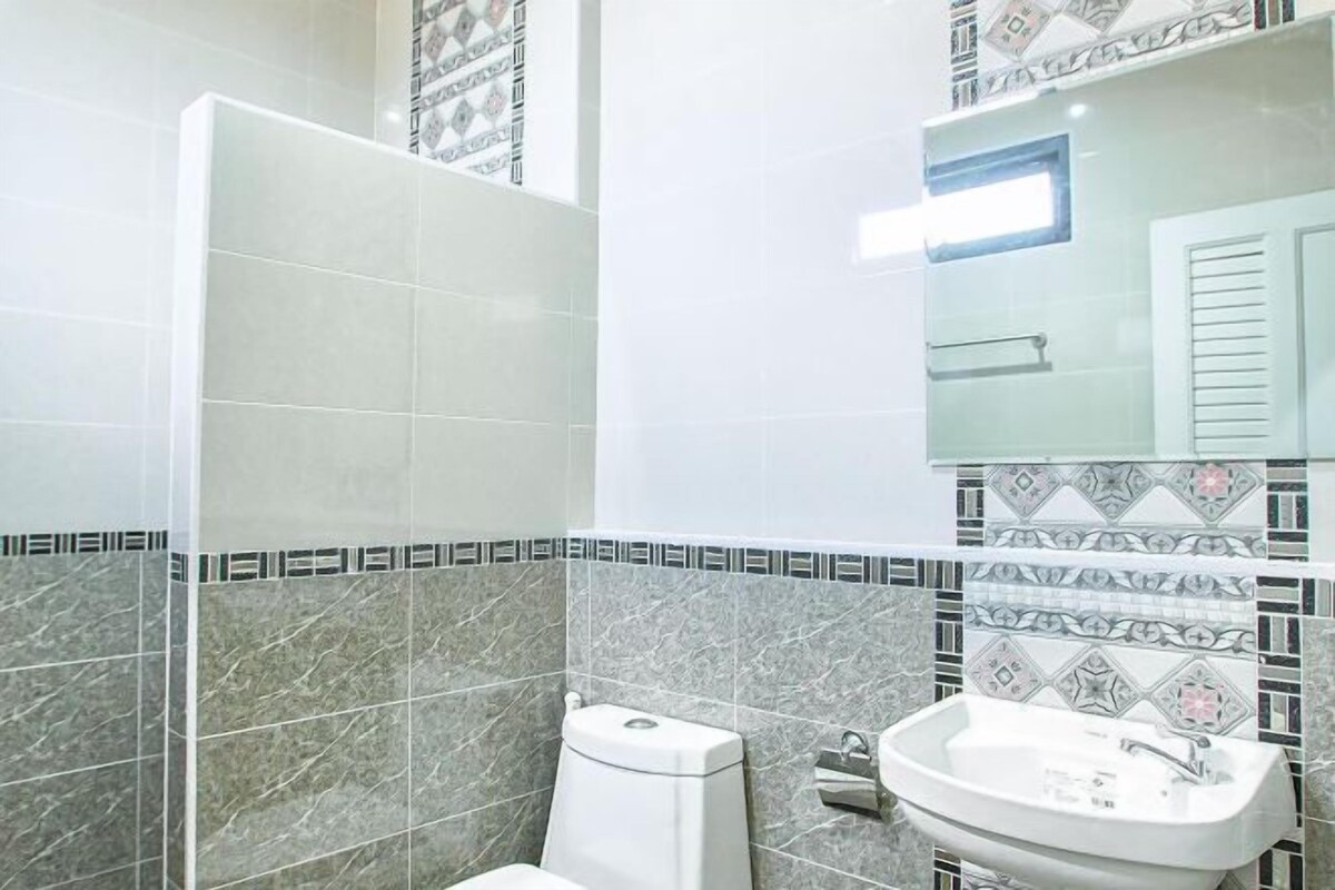 Une salle de bain équipée de toilettes, d’un lavabo et d’un mur recouvert de carreaux décoratifs.