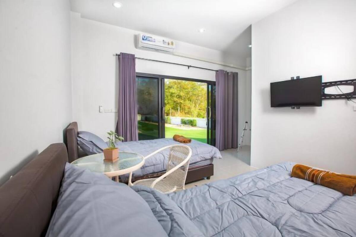 Una habitación de hotel moderna con cama, sofá, una mesita y televisor montado en la pared.