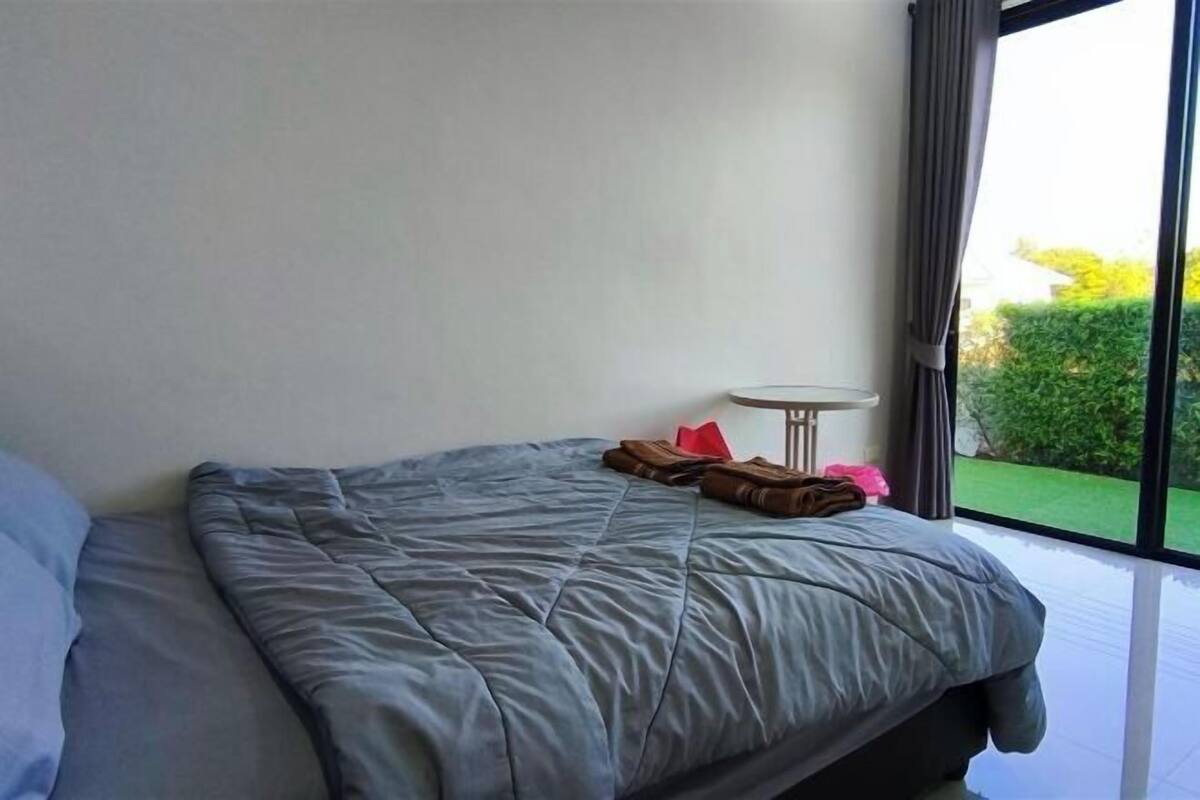 Un dormitorio con cama, una mesita redonda y vistas al verdor exterior.