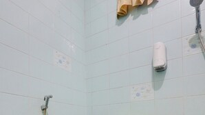 A bathroom with a toilet, a shower, and a towel hanging on the wall. - Hotel O Omah Citra Genia Homestay (Ngaglik)