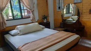 A bedroom with a bed, a nightstand, a mirror, and a window with curtains. - Hotel O Omah Citra Genia Homestay (Ngaglik)