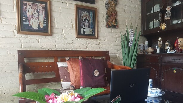 A room with a wooden desk, a laptop, a decorative plant, and a traditional chair. - Hotel O Omah Citra Genia Homestay (Ngaglik)