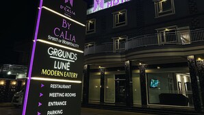 Letrero de hotel con "Hotel D'Calia" y "Spirit of Hospitality" resaltados en luces de neón.