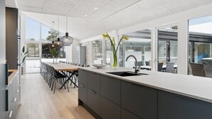 Une cuisine moderne dotée d’un long comptoir, d’un évier et d’un coin repas avec des chaises.